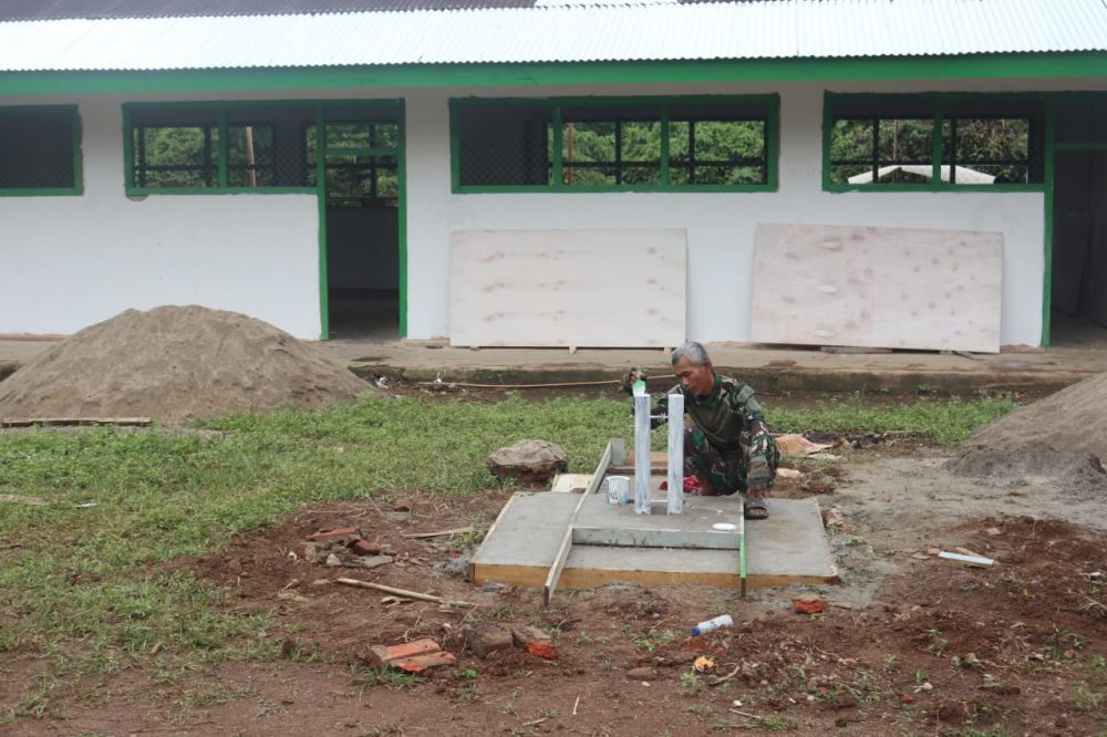 Anggota Satgas TMMD ke 123 Membuat Tapak dan Dudukan Tiang Bendera Upacara di Halaman Madrasah Ibtidaiyah Nurul Falah Teluk Kuali